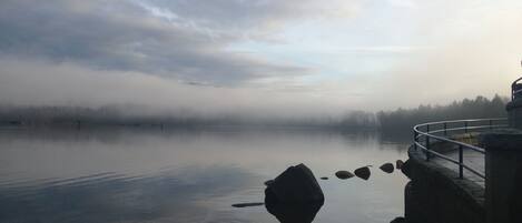 A calm lake with a stone structure and a metal railing on the right.