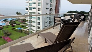 A balcony with a view of a swimming pool and a garden, furnished with a table and chairs. - Paradise at Shangrila, Beachfront (Puerto Vallarta)