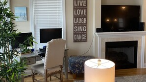 A living room with a TV, a fireplace, a motivational quote wall, a lamp, a chair, a sofa, and a potted plant. - Great Location - Close to Beach, Boardwalk, Asbury Shops and Cafes! (Ocean City)