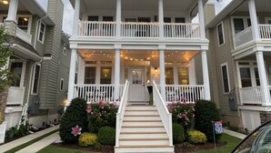 A two-story house with a front porch, a staircase leading to the entrance, and a small garden with flowers and shrubs. - Great Location - Close to Beach, Boardwalk, Asbury Shops and Cafes! (Ocean City)