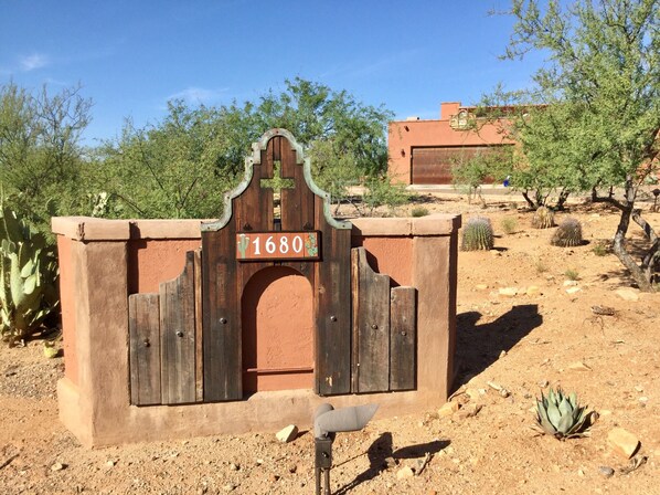 A rustic wooden gate with a sign reading "1680" in a desert landscape with cacti and a building in the background. - Unique, Custom Built Studio for your Private Peaceful Retreat (Green Valley)