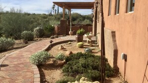 A courtyard with a brick pathway, potted plants, and a pergola. - Unique, Custom Built Studio for your Private Peaceful Retreat (Green Valley)