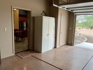 A garage with a sliding door, a white cabinet, and a dining area with a table and chairs. - Unique, Custom Built Studio for your Private Peaceful Retreat (Green Valley)