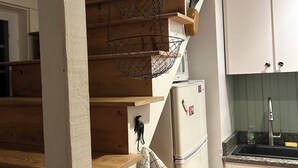 Una cocina con escaleras de madera, una cesta colgante, una toalla y un refrigerador.