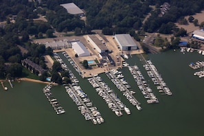 Boats docked in a well-organized marina, surrounded by lush greenery and commercial buildings.