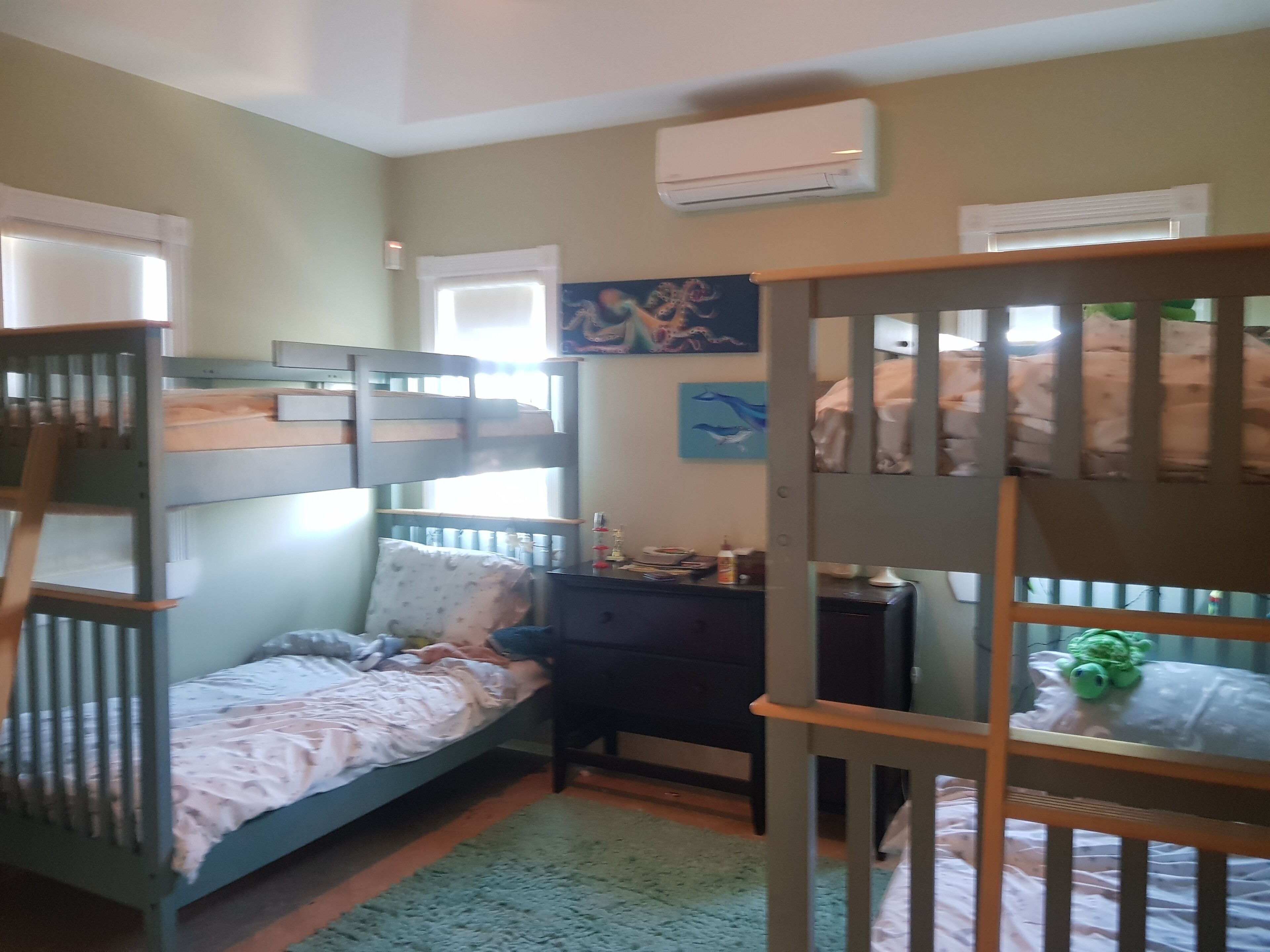 Ein Schlafzimmer mit Etagenbetten, einem Schreibtisch und einer Klimaanlage.