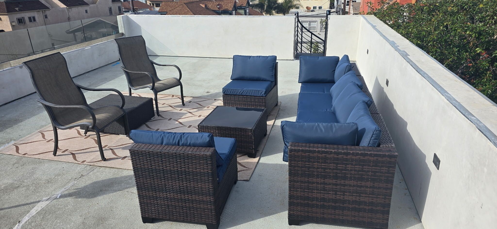 A rooftop terrace with wicker furniture and blue cushions.