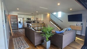 Een moderne woonkamer met een bank, een potplant en een trap naar een keuken.