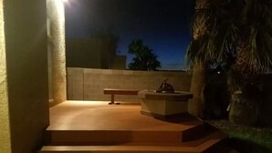 A set of wooden steps leading to a patio area with a stone bench and a small table.