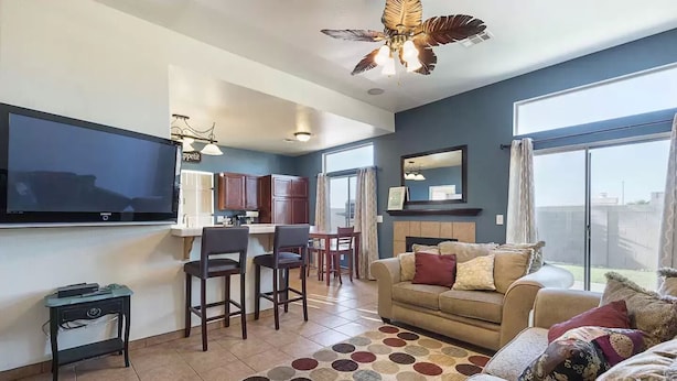 A living room with a TV, a sofa, a coffee table, and a dining area with chairs.
