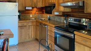 Una cocina con armarios de madera, electrodomésticos de acero inoxidable y un candelabro.