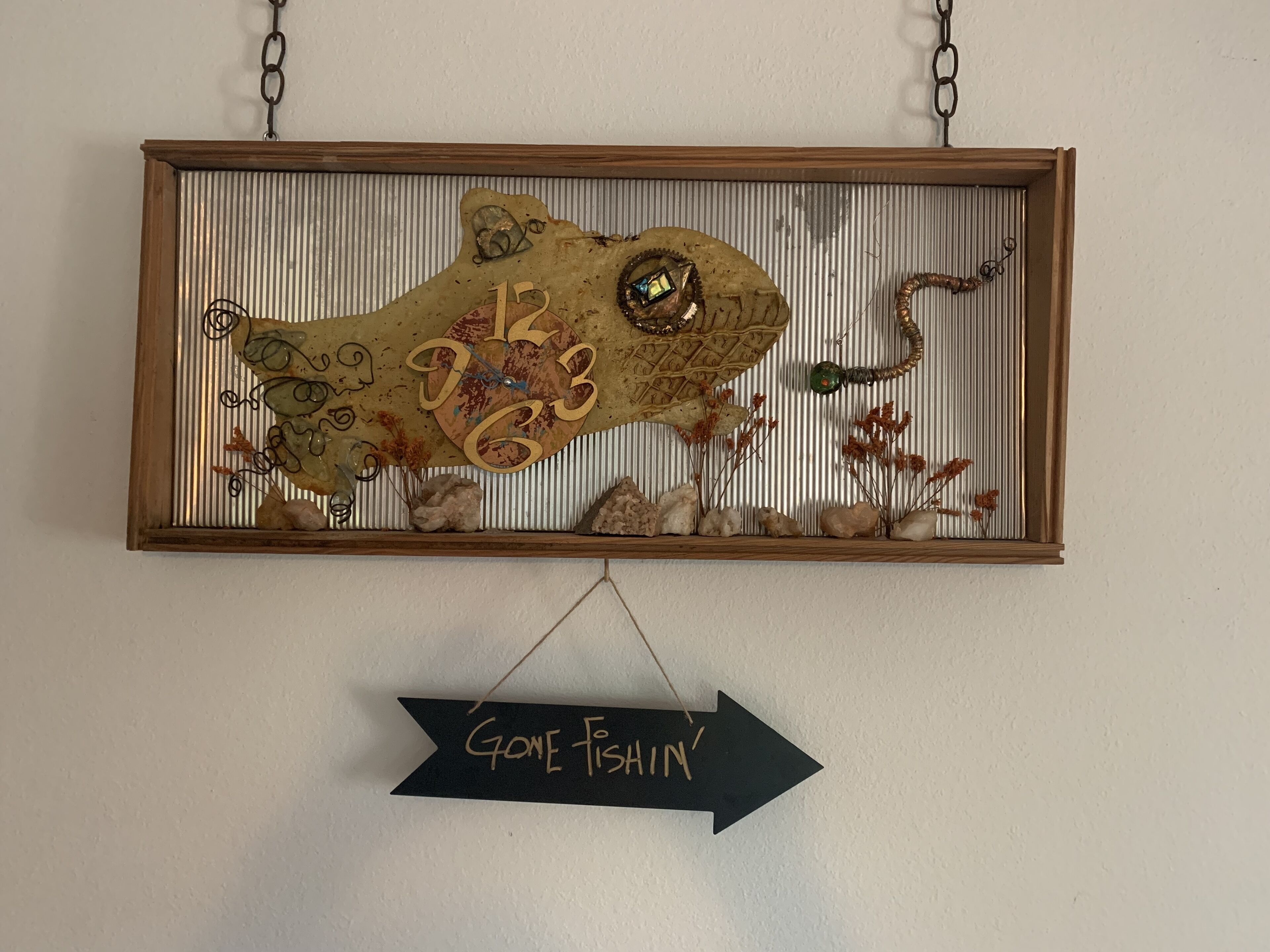 A wall-mounted decorative piece with a clock and a sign below it.