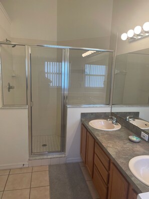 A bathroom with a glass-enclosed shower, two sinks, a vanity with cabinets, and a large mirror with lights. - OAK ISLAND COVE!   BEAUTIFUL POOL HOME with free Pool heat and Wifi (Kissimmee)