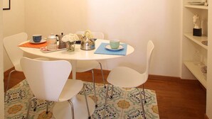 A dining area with a round table, white chairs, a patterned rug, and artwork on the walls. - CasaCaterina, in the Heart of the Old Center of Florence (Firenze)