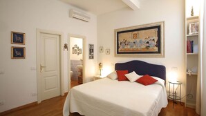 A bedroom with a bed, a painting, a bookshelf, and a door. - CasaCaterina, in the Heart of the Old Center of Florence (Firenze)