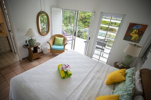 Ein Hotelzimmer mit Bett, Sessel, Tisch mit Lampe und Blick ins Freie.