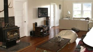 Un salon avec une cheminée, un téléviseur, un canapé et un ventilateur de plafond.