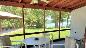 A covered patio with a round table and four chairs, overlooking a grassy area and a body of water. - Clean, family/pet friendly AR Ozark Mountain/Norfork Lake Front Cabin (Gamaliel)