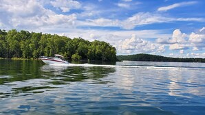 A boat on a calm lake with a forested island in the background. - Clean, family/pet friendly AR Ozark Mountain/Norfork Lake Front Cabin (Gamaliel)