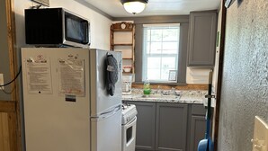 A compact kitchen with a refrigerator, microwave, oven, and a window with blinds. - Clean, family/pet friendly AR Ozark Mountain/Norfork Lake Front Cabin (Gamaliel)