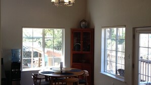 A spacious room with a wooden ceiling, a dining table with chairs, a water dispenser, and a cabinet.
