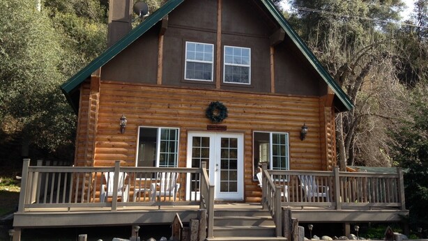 A wooden cabin with a front porch, two windows, and a door.
