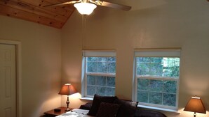 A bedroom with a bed, two windows, a ceiling fan, and two bedside lamps.