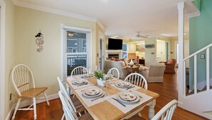 A dining area with a wooden table set for four, surrounded by white chairs. - The FAMILY Spot in Wild Dunes - Walking Distance to Beach - Pool Access (Isle Of Palms)