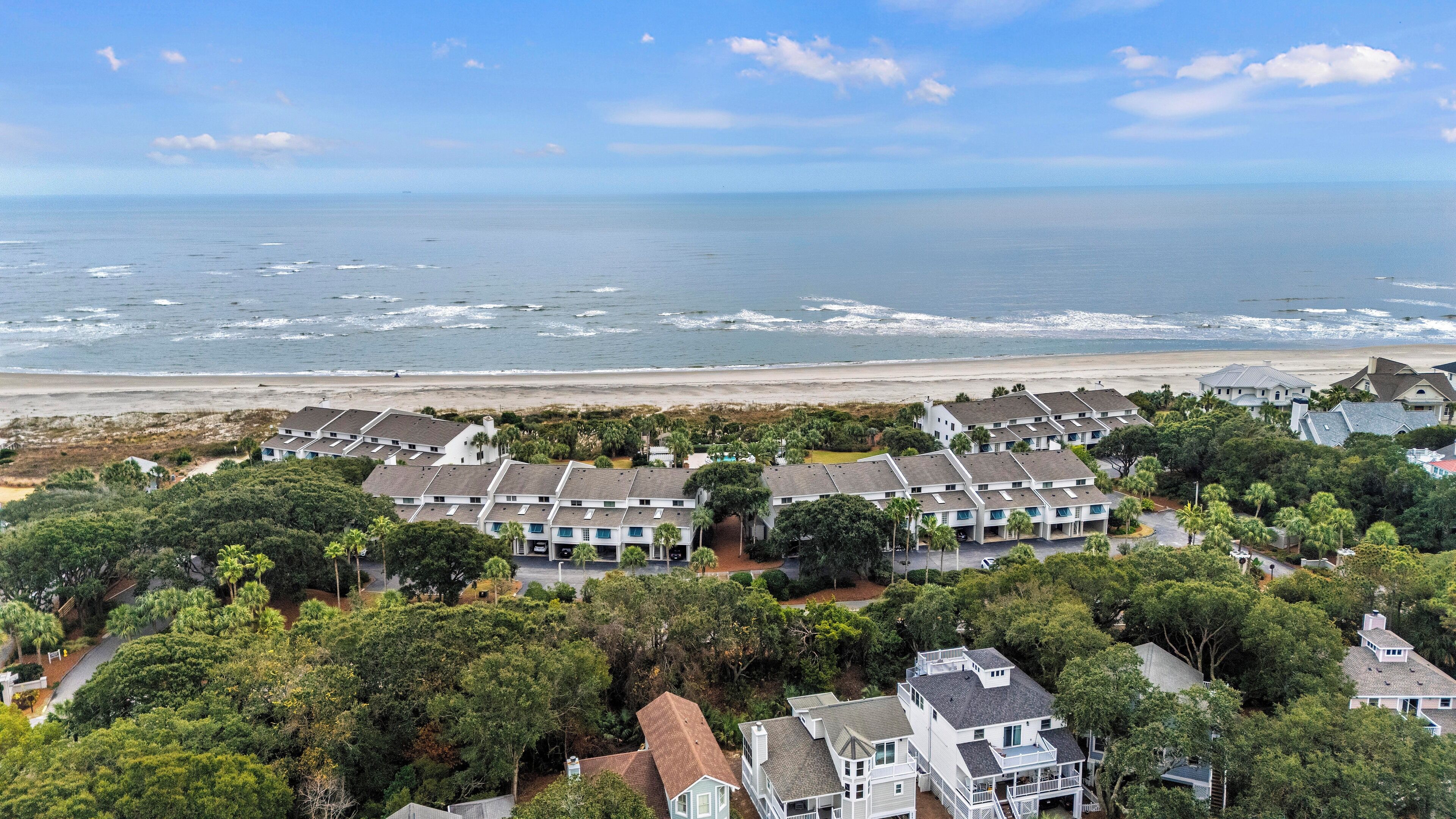 Una zona residencial costera con casas de varios pisos, una playa y una vista despejada del océano.