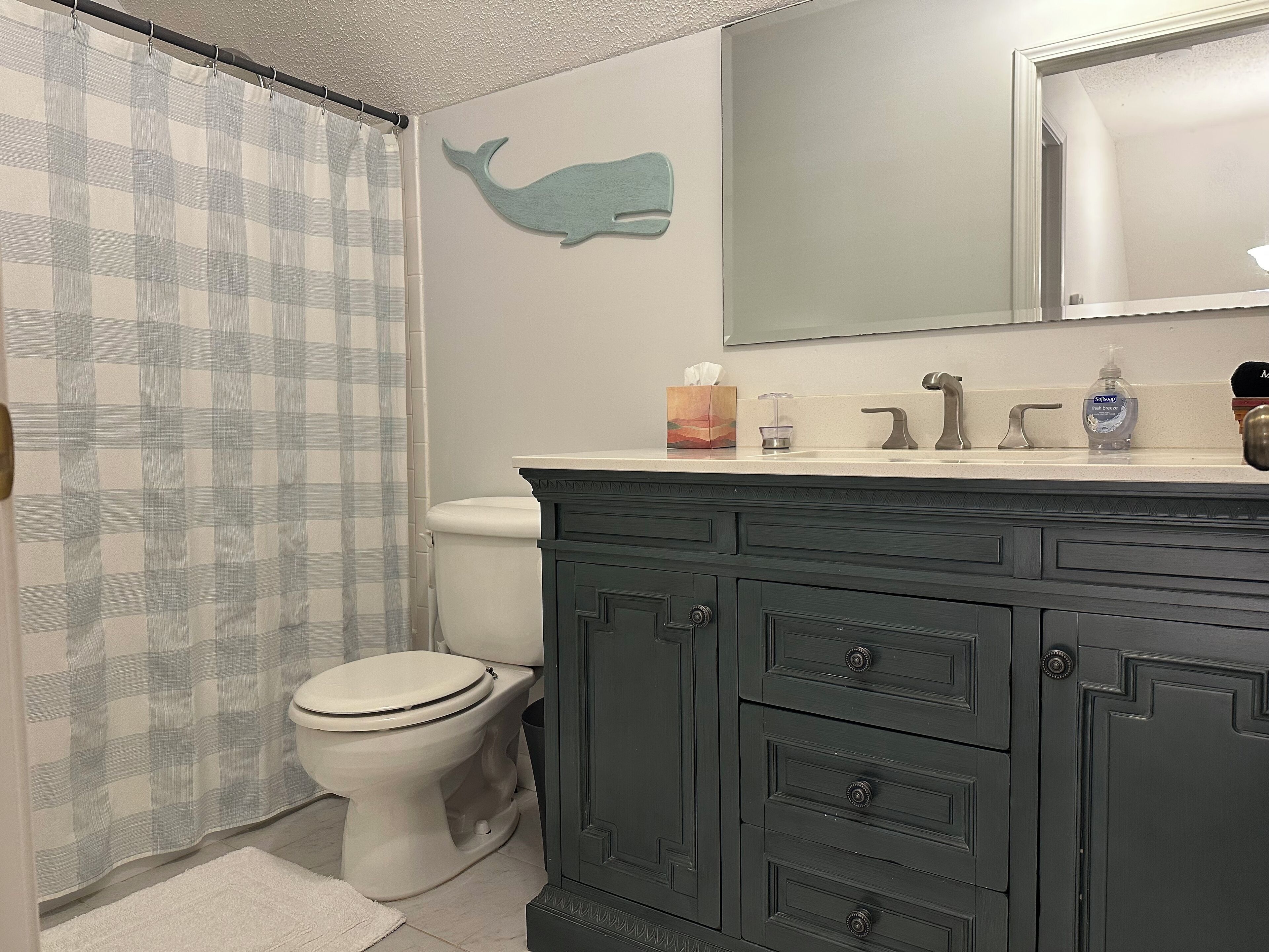A bathroom with a toilet, a dark wooden vanity, a mirror, and a wall-mounted whale decoration.