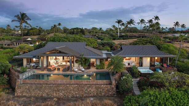 A modern house with a large pool, outdoor seating, and lush landscaping.