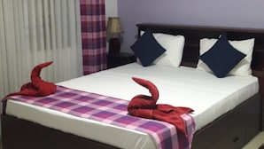 A hotel room with a large bed, a nightstand, a lamp, a painting on the wall, and a window with curtains.