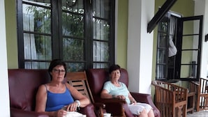 Two people seated on a sofa in a room with a tiled floor and a potted plant.