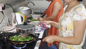 A kitchen with a stove, pots, and a person cooking.