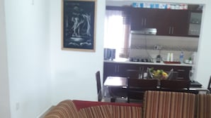 A living room with a sofa and a child sitting on it. There is a kitchen in the background.