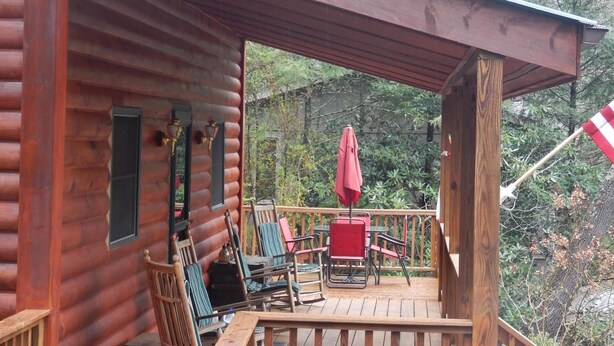Een houten terras met buitenmeubilair en een rode parasol.