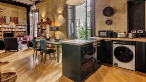 A modern kitchen with a built-in washer and dryer, a dining area with chairs and a table, and a large window providing natural light. - Historical apartment in the heart of Florence with exclusive terrace (Firenze)