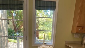 Ein Essbereich mit Holztisch, Stühlen und einem Fenster mit Blick ins Grüne.