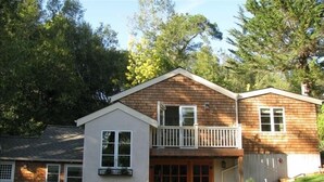 Ein zweistöckiges Haus mit Veranda, Garage und kleiner Terrasse.