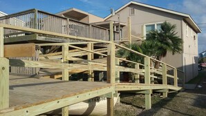 Eine Holzterrasse mit einer Treppe, die zu einem Gebäude mit einem Balkon führt.