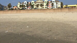 Een hotel aan het strand met meerdere kleurrijke gebouwen, een zandstrand en een helderblauwe lucht.