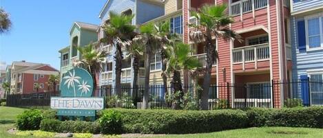 A row of colorful condominiums with a sign for 'The Dawn' in front.