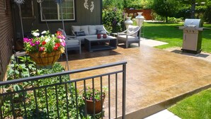 A patio with outdoor furniture, a grill, and potted plants.