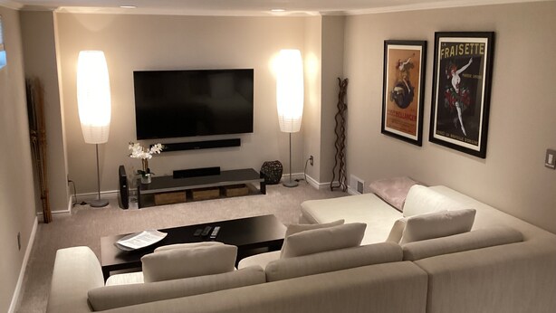 A modern living room with a large flat-screen TV, a sofa, a coffee table, and two floor lamps.