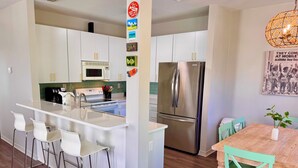 A modern kitchen with white cabinets, stainless steel appliances, and a bar area with stools.