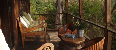 A wooden deck with a sofa, a chair, and a small table with a plant.