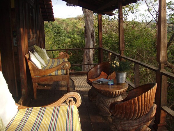 A wooden deck with a sofa, a chair, and a small table with a plant.