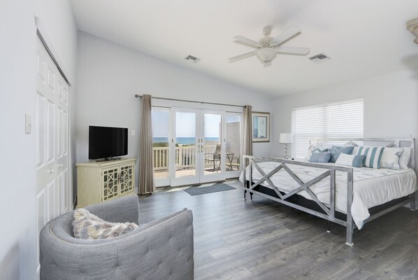 A bedroom with a bed, a television, a chair, and a balcony with a view. - Oceanfront! Fenced in back yard! Pet Friendly! Come visit anytime👍 (Brigantine)