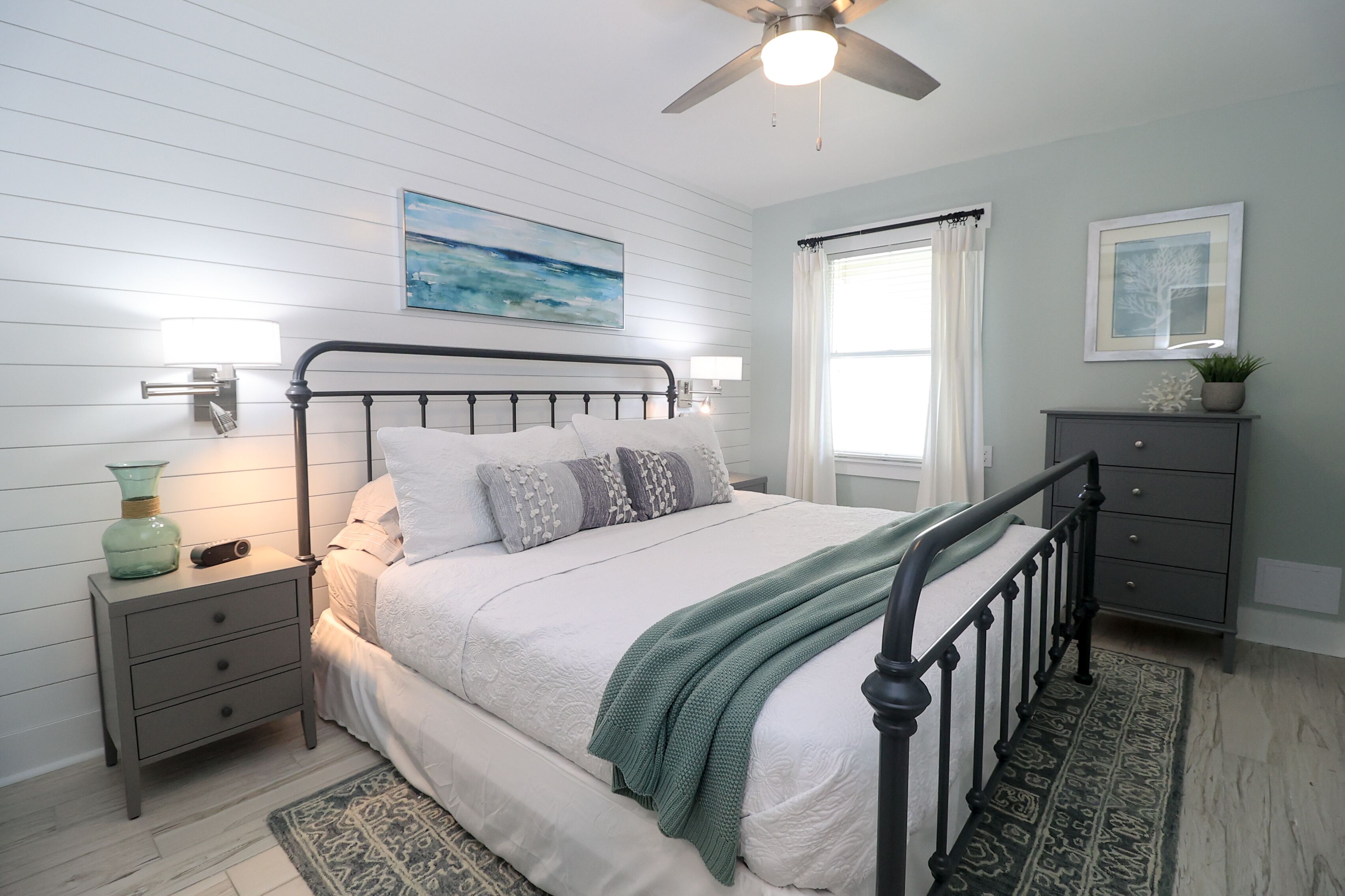 A bedroom with a bed, nightstand, dresser, and a ceiling fan.