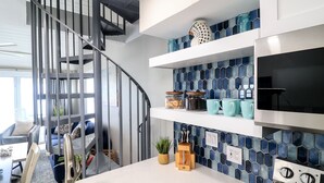 Una cucina moderna con lavello in acciaio inossidabile, piano cottura integrato e zoccolo a mosaico blu.